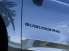 2021-chevrolet-suburban-z71-shadow-gray-metallic-gji-press-photos-exterior-019-black-suburban-logo-badge-on-door