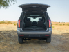 2021-chevrolet-tahoe-z71-middle-east-exterior-020-rear-end-dirt-road-liftgate-open-third-row-folded