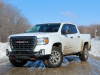 2021-gmc-canyon-at4-summit-white-crew-cab-short-bed-gma-garage-exterior-009-front-three-quarters-dirt-road