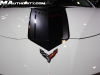 2022-chevrolet-corvette-stingray-arctic-white-with-carbon-fiber-accessories-2021-sema-live-photos-exterior-001-stingray-r-visible-graphics-package-corvette-crossed-flags-logo-in-carbon-flash-on-front