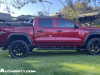 2023-chevrolet-colorado-trail-boss-radiant-red-tintcoat-gnt-first-drive-exterior-005-side-accessory-wheels-steps-exhaust-tip-tonneau-cover-removable-rail-kit-by-thule-surf-board