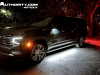 2023-chevrolet-suburban-high-country-gma-garage-night-time-lights-exterior-001-side-front-three-quarters
