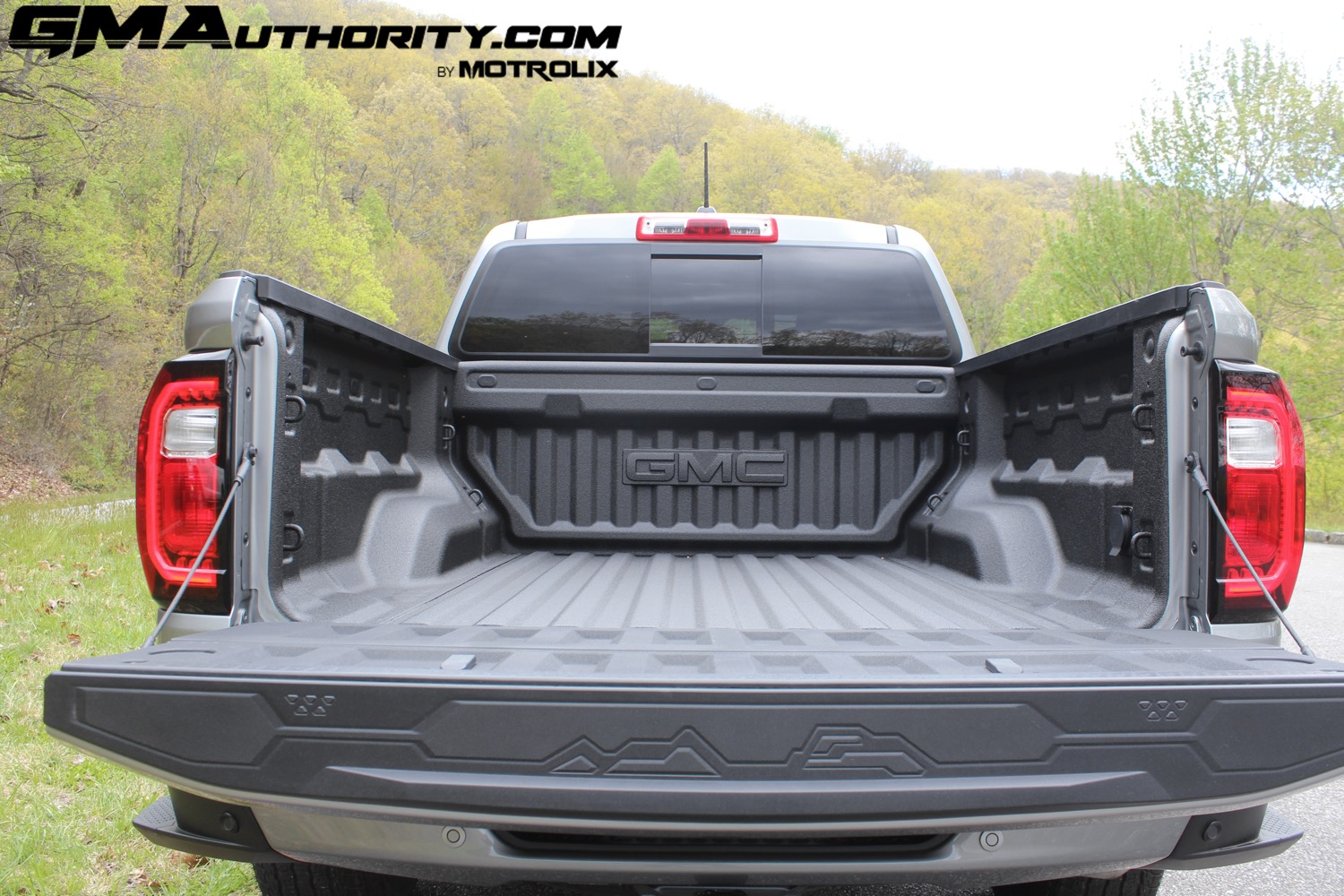 2023-gmc-canyon-elevation-sterling-metallic-gxd-first-drive-exterior-085-tailgate-open-mountain-graphic