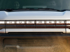 2024-gmc-hummer-ev-suv-exterior-020-front-driving-through-mud-hummer-logo-on-grille