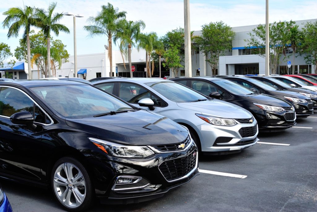 Car dealerships with a row of Chevy Cruze cars in stock.