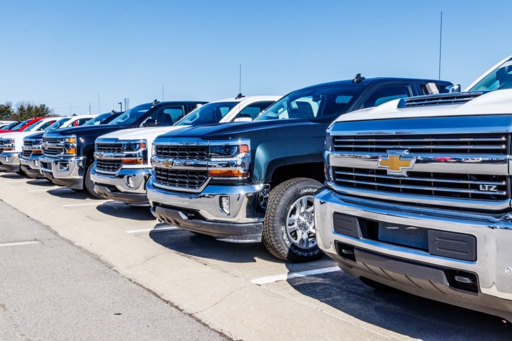 Chevy Silverado trucks lined up at a used car dealership.