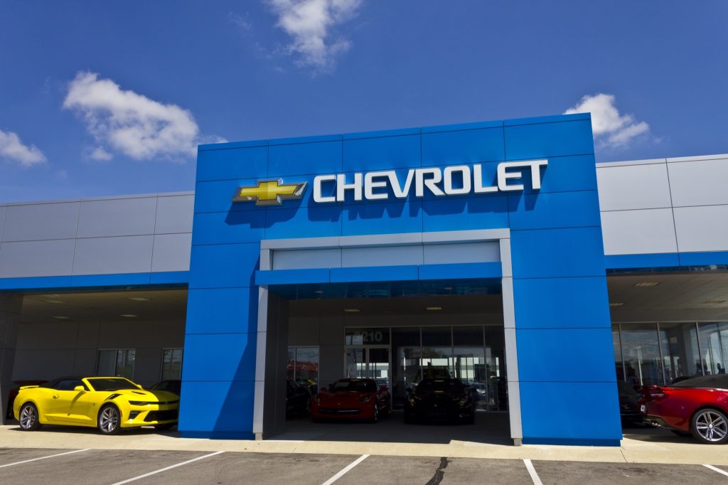 The storefront of a Chevy dealer under a blue cloud-dotted sky.