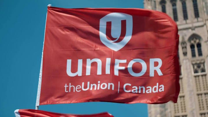 A Unifor flag is flown at a demonstration.