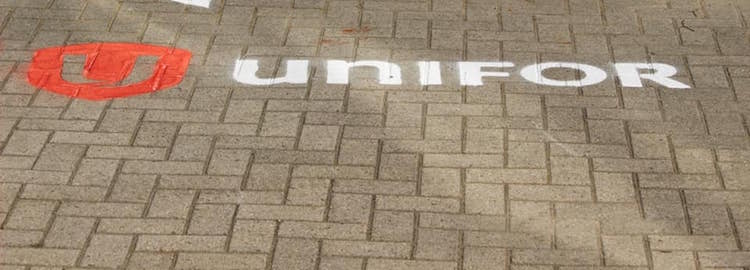The Unifor logo is spray-painted on the ground.