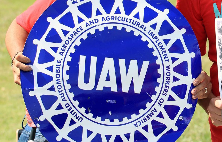 A GM worker holding a UAW sign during a strike.