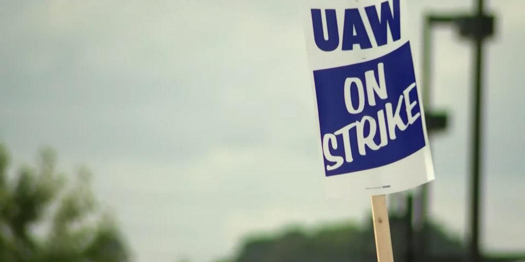 A UAW member holds a strike sign.