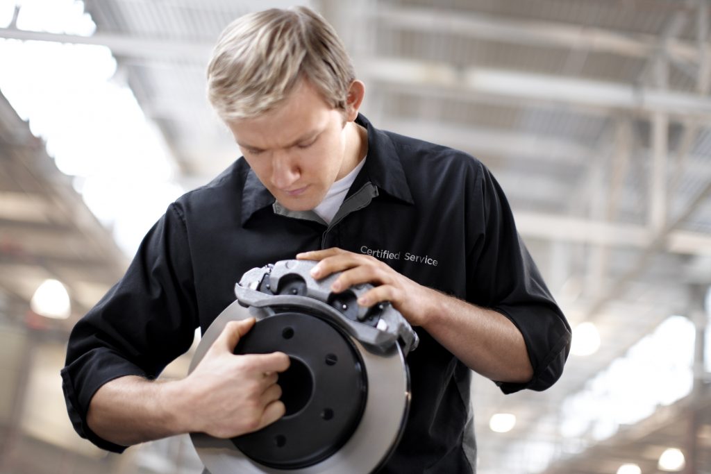 An automotive technician fits a brake caliper.