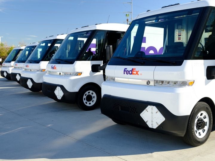 A lineup of Chevy BrightDrop vans with the FedEx logo. 