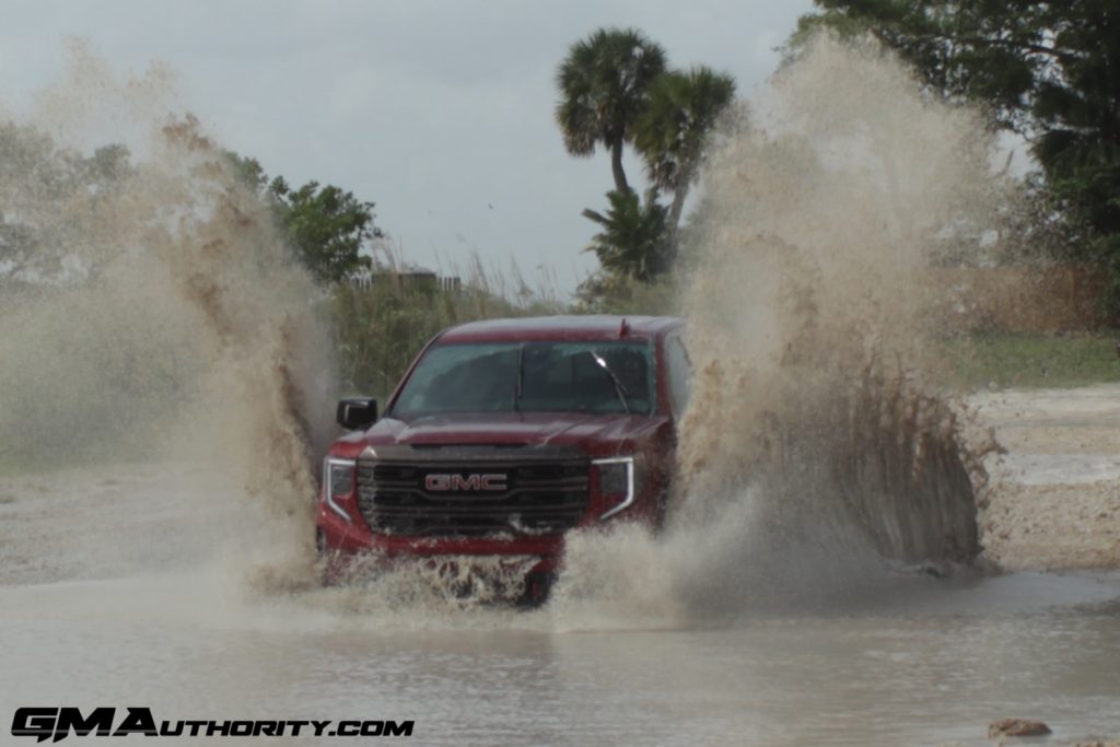 A photo of the 2022 GMC Sierra 1500 AT4X driving through a mud puddle.