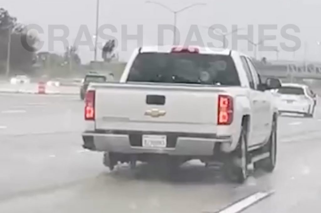 The rear end of a Chevy Silverado rolling down the freeway on only three wheels.