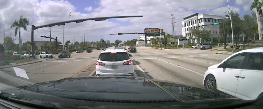 Screenshot showing a Chevy Equinox, which ends up blindly passing another vehicle and causes a motorcycle to crash.