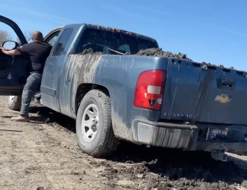 Screenshot from a viral video showing a mud-laden Chevy Silverado pickup truck used to dam a levee.