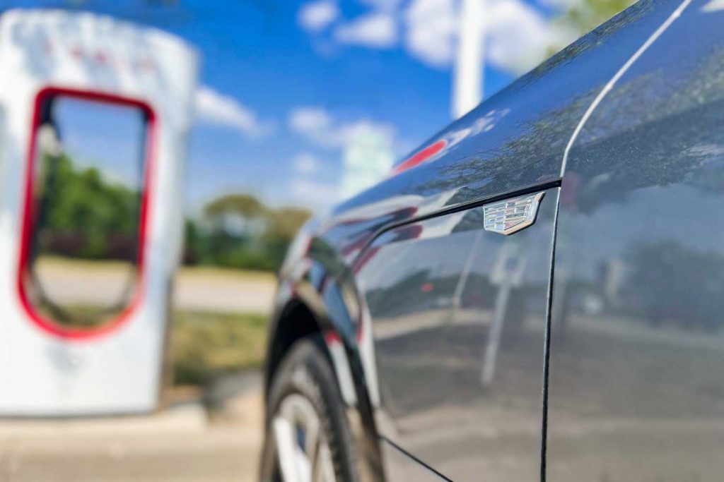 A Cadillac Lyriq parked at a Tesla Supercharger station.