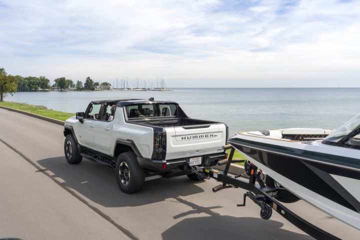 Rear-three-quarter view of GMC Hummer EV Pickup towing a boat.