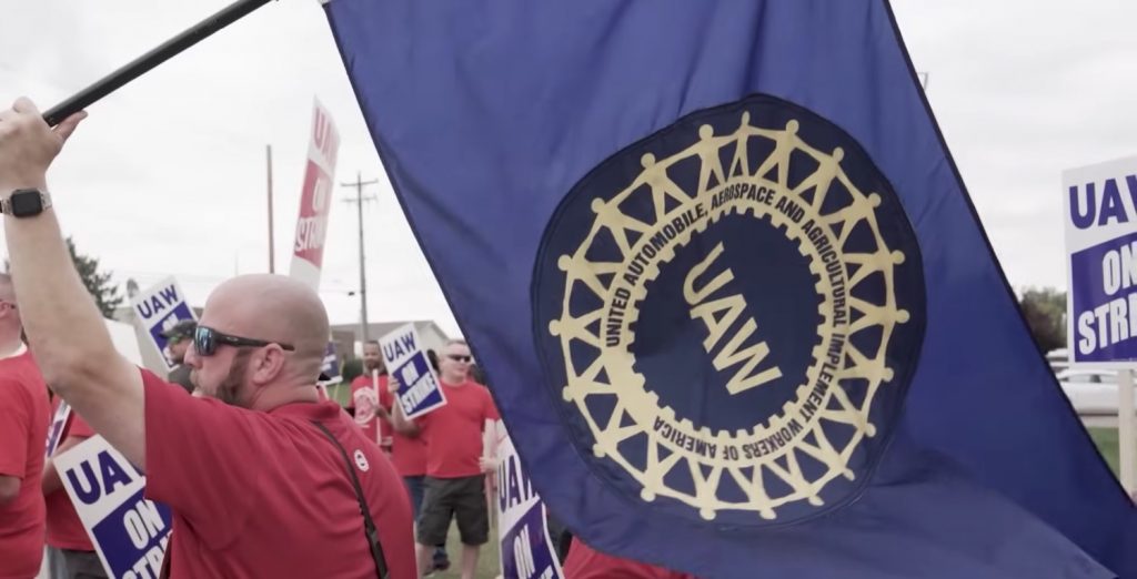 A UAW union member holds a UAW flag at a demonstration.