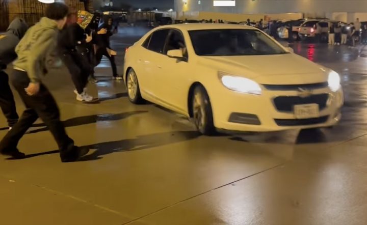 A Chevy Malibu slides around a Dodge Challenger.