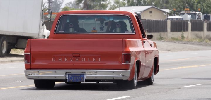 A custom Chevy truck accelerates down a public road.