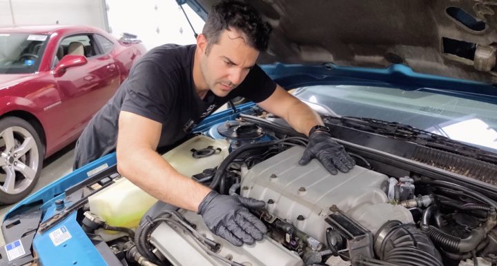 A mechanic explores the engine bay of a 1992 Oldsmobile Cutlass Supreme.