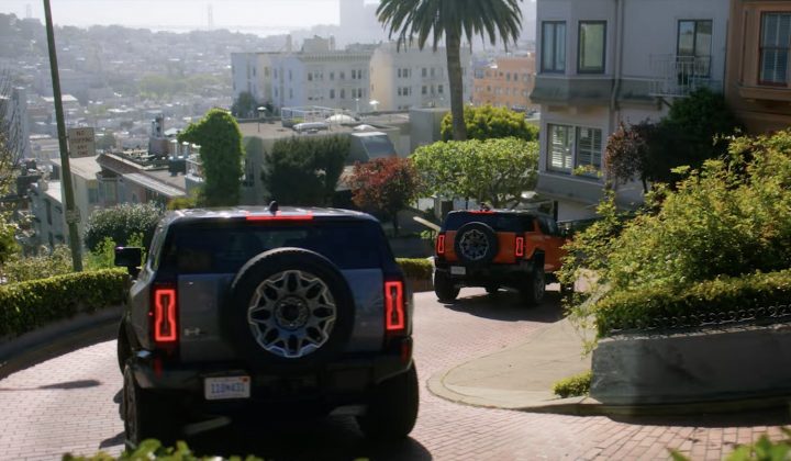 Two units of the 2025 GMC Hummer EV SUV driving downhill.