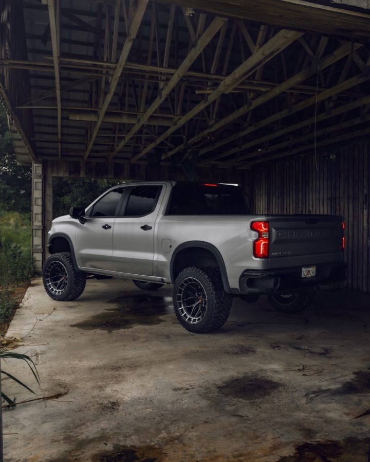 A Chevy Silverado ZR2 on custom wheels, parked in a barn.