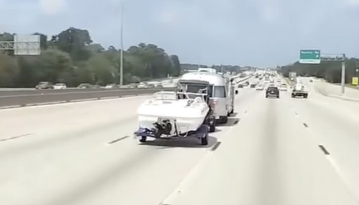 A Chevy Silverado pulls a boat, a UTV, and a camper in tandem.