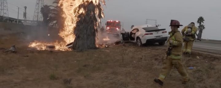 Fire fighters work to extinguish a blazer caused by a wrecked Chevy Camaro.