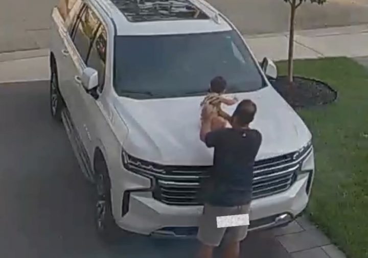 A father places his child on the hood of a Chevy Suburban.