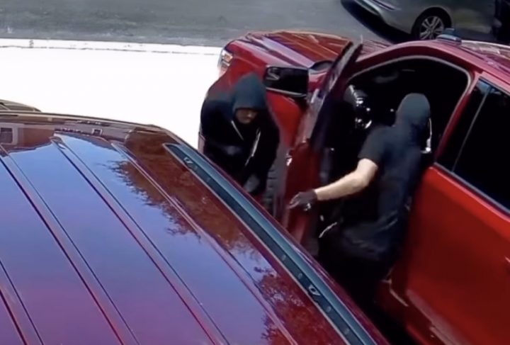 Thieves breaking into a GMC Sierra pickup truck.