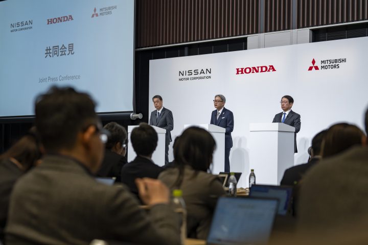 Honda, Nissan, and Mitsubishi executives at a press conference.