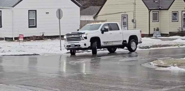 A white Chevy Silverado HD slides on an icy road.