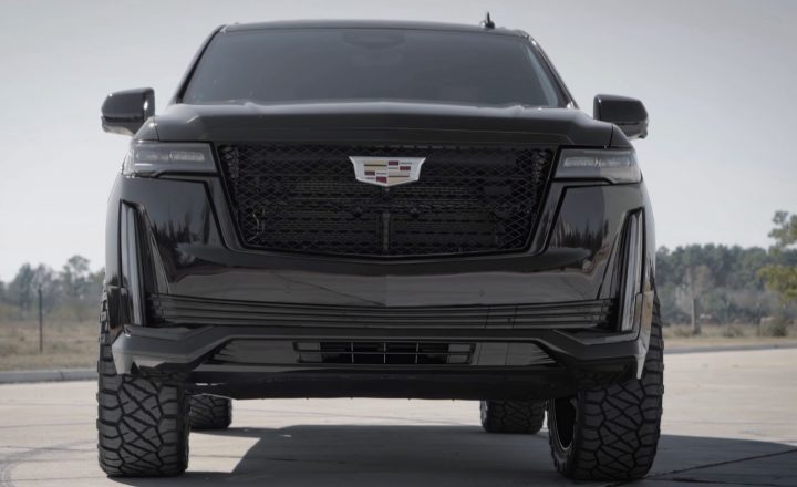 The front end of a lifted and blacked-out Cadillac Escalade.
