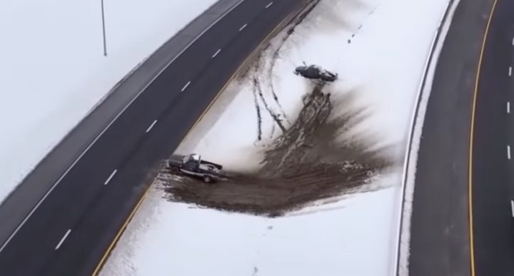 A GMC Sierra driver attempts to merge onto a freeway up a muddy incline.