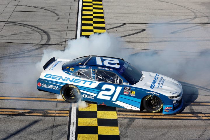 Photo showing Austin Hill, driver of the No. 21 NASCAR Chevy, celebrating after winning the Xfinity Series race at Talladega in a photo finish.