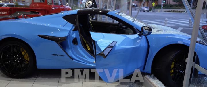 A blue C8 Corvette Z06 stuck in a dealership window frame.