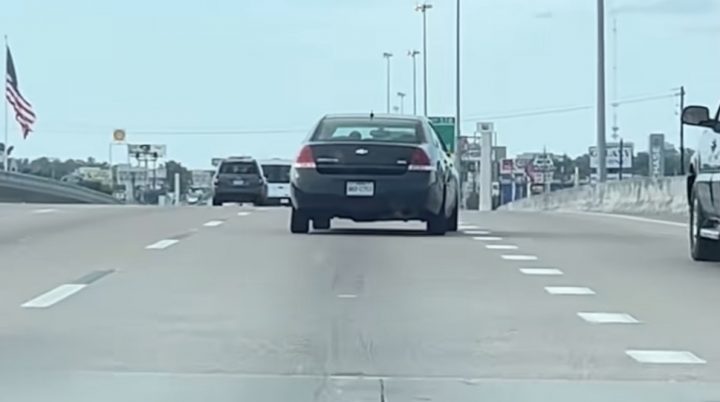 A Chevy Impala with a bent frame travels down a highway in Houston.