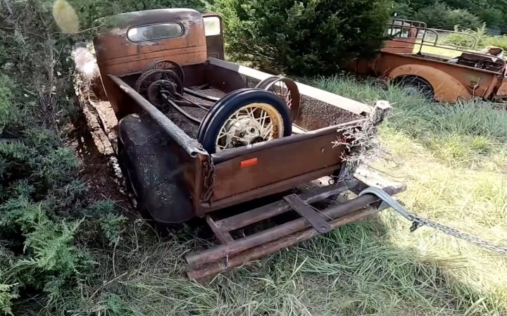 An old GMC truck is pulled out from some weeds.